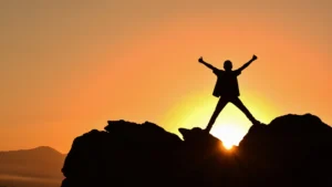 man standing on a rock arms spread overcome fear